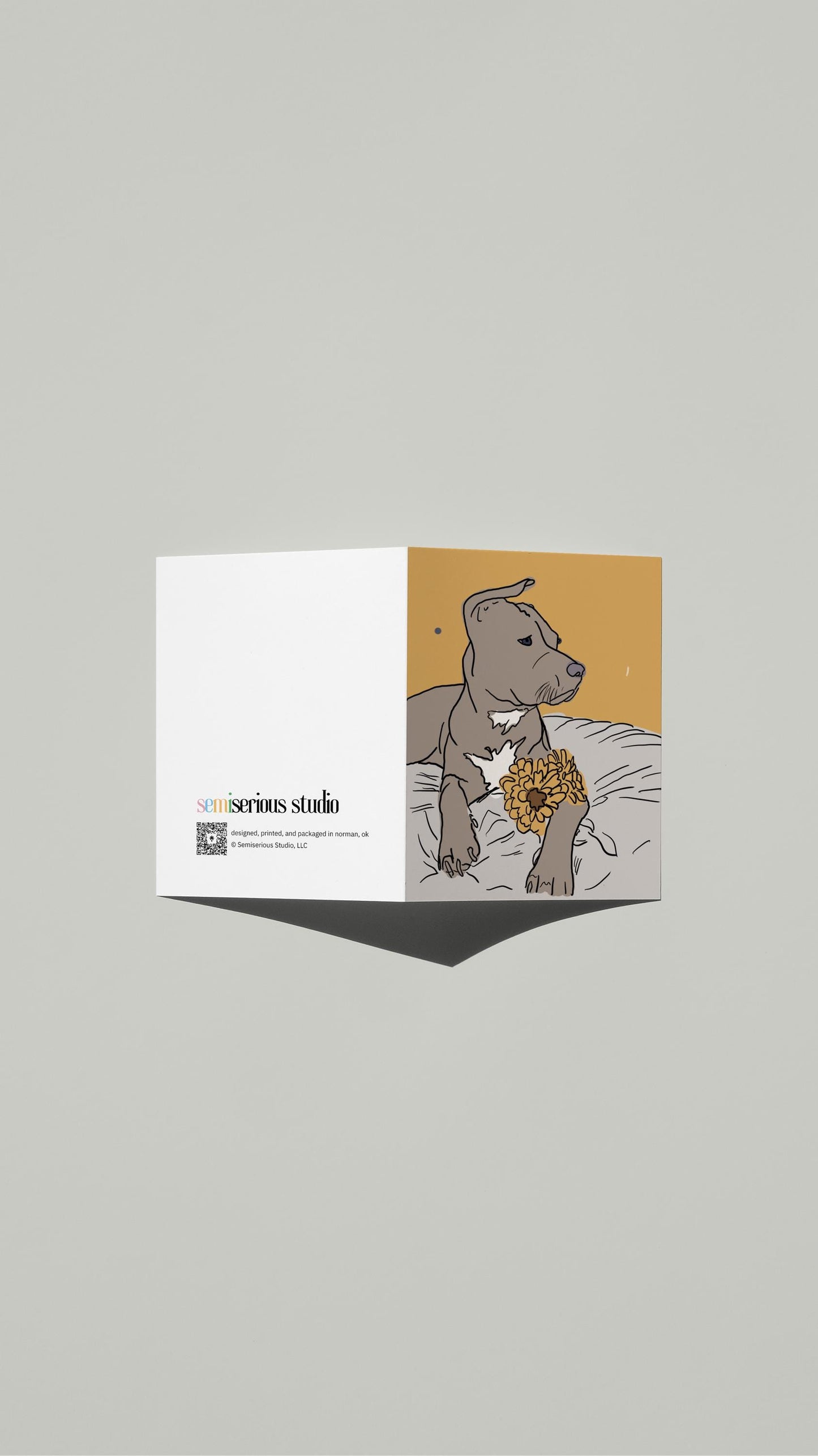 Dog with Flowers Just Because card standing open, showing the front artwork and the Semiserious Studio logo on the back