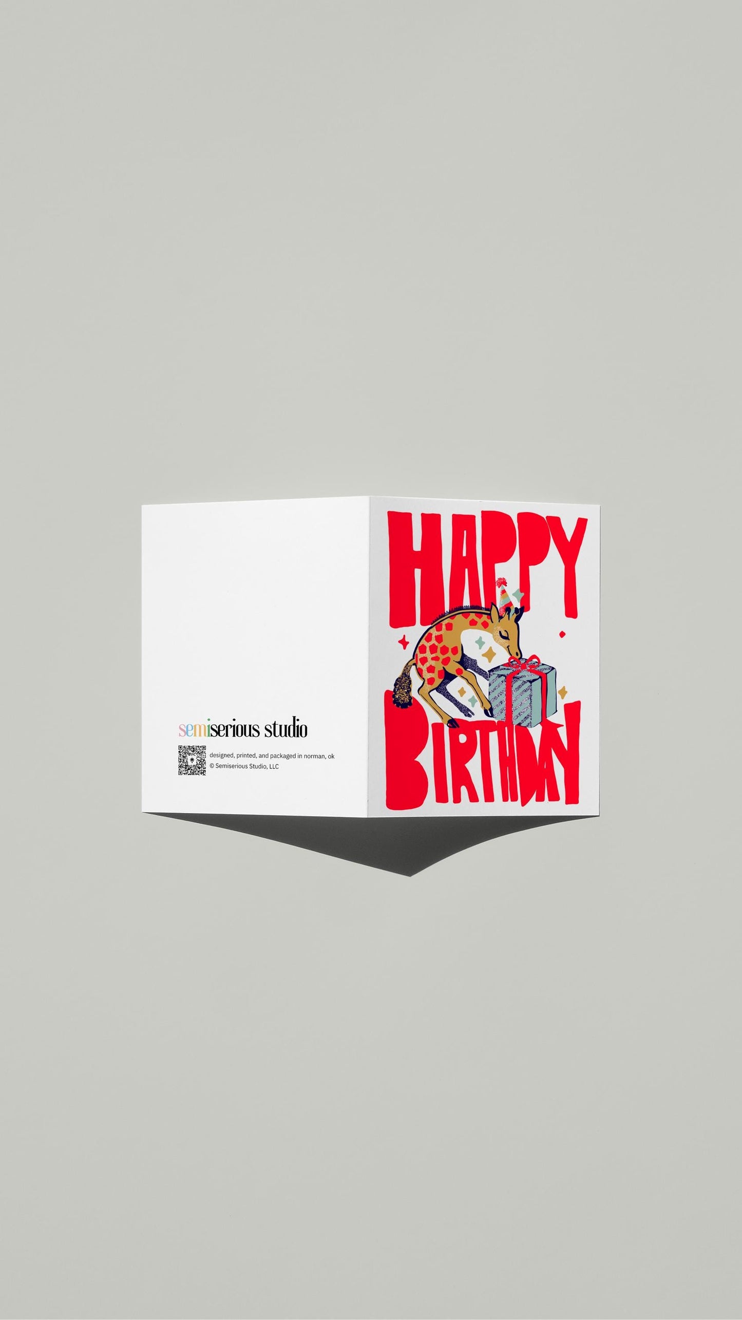 Giraffe Birthday card standing open, showing the front artwork and the Semiserious Studio logo on the back