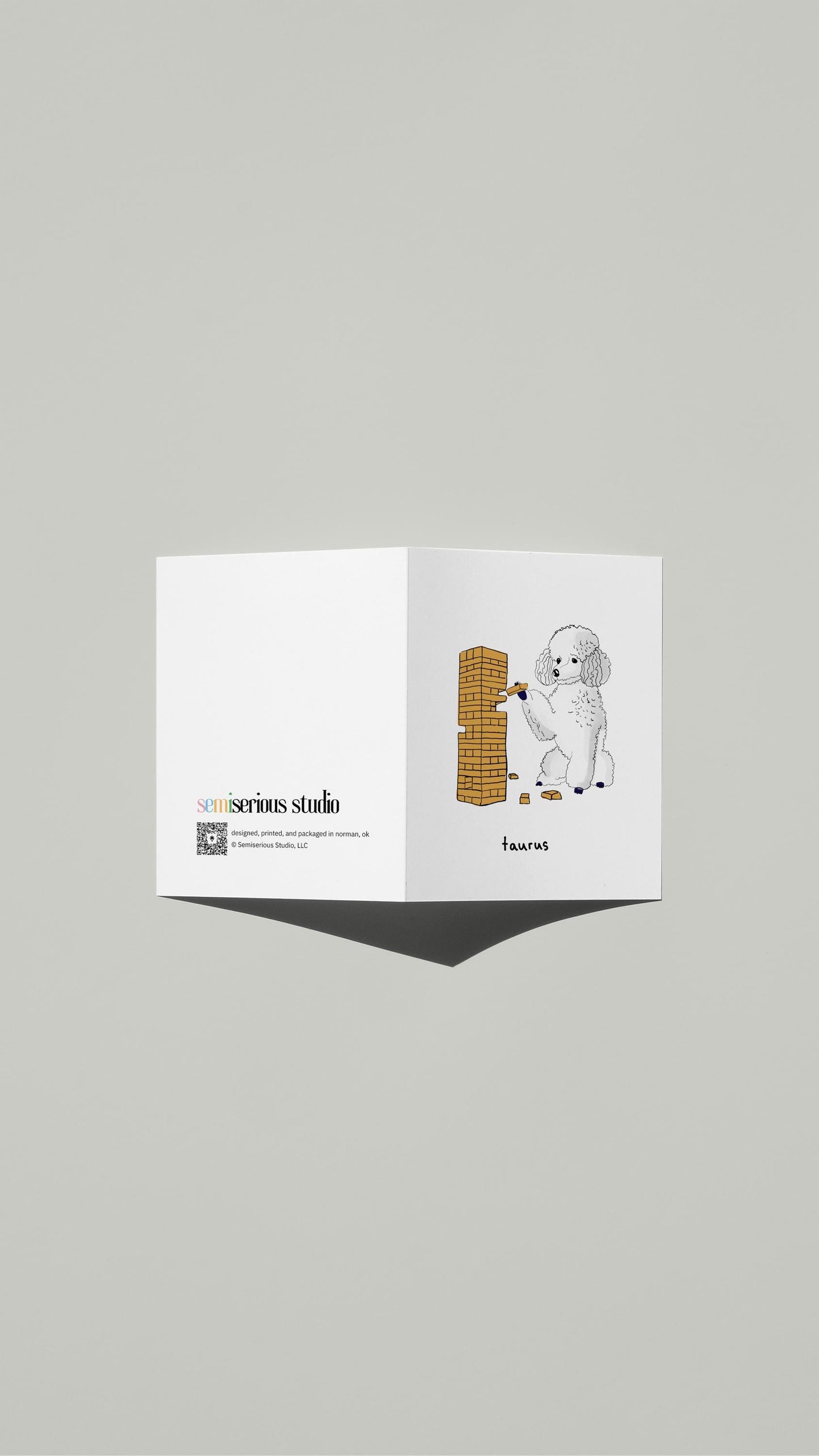 Taurus Poodle Jenga Birthday card standing open, showing the front artwork and the Semiserious Studio logo on the back