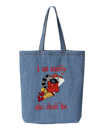 Denim tote bag printed with a raccoon in a cowboy hat and red boots leaning back, with the words i am exactly who i should be
