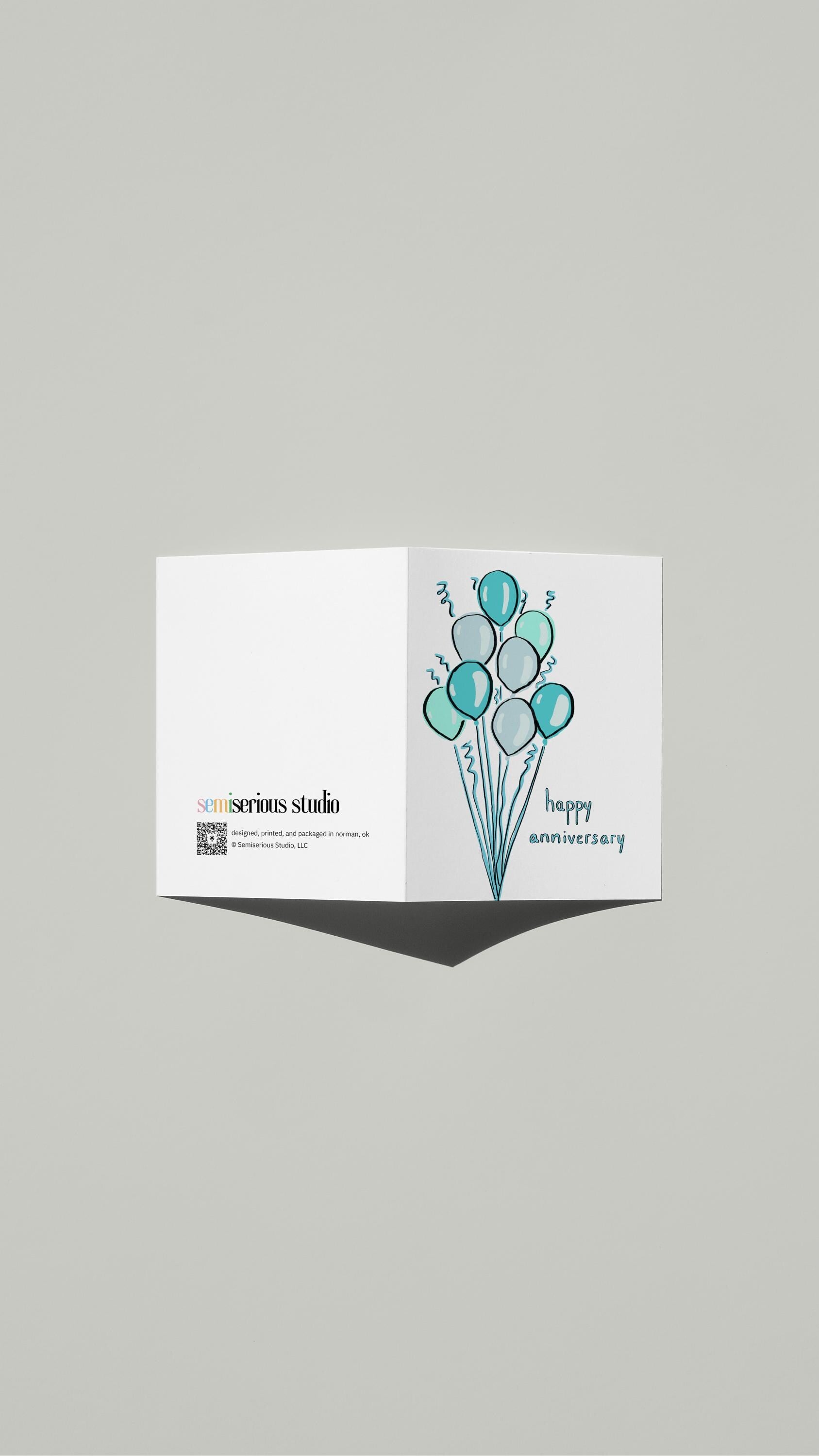 Blue Balloons Anniversary card standing open, showing the front artwork and the Semiserious Studio logo on the back