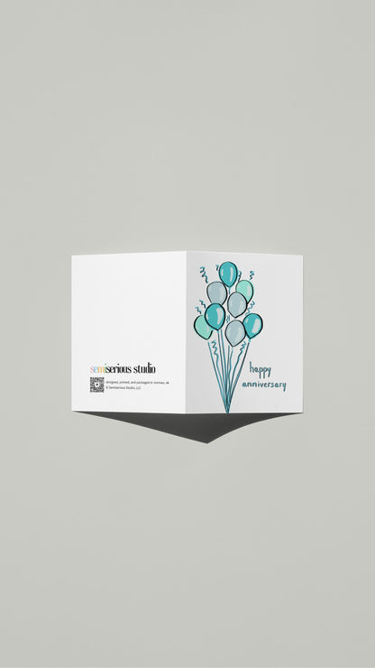 Blue Balloons Anniversary card standing open, showing the front artwork and the Semiserious Studio logo on the back