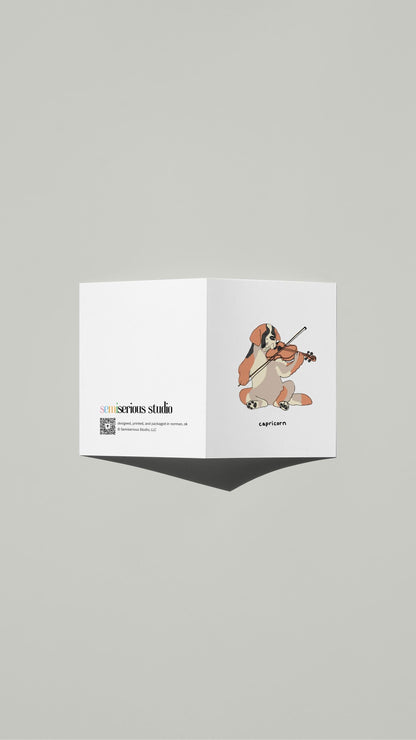 Capricorn St. Bernard Violin Birthday card standing open, showing the front artwork and the Semiserious Studio logo on the