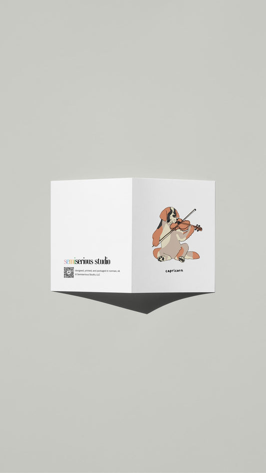 Capricorn St. Bernard Violin Birthday card standing open, showing the front artwork and the Semiserious Studio logo on the