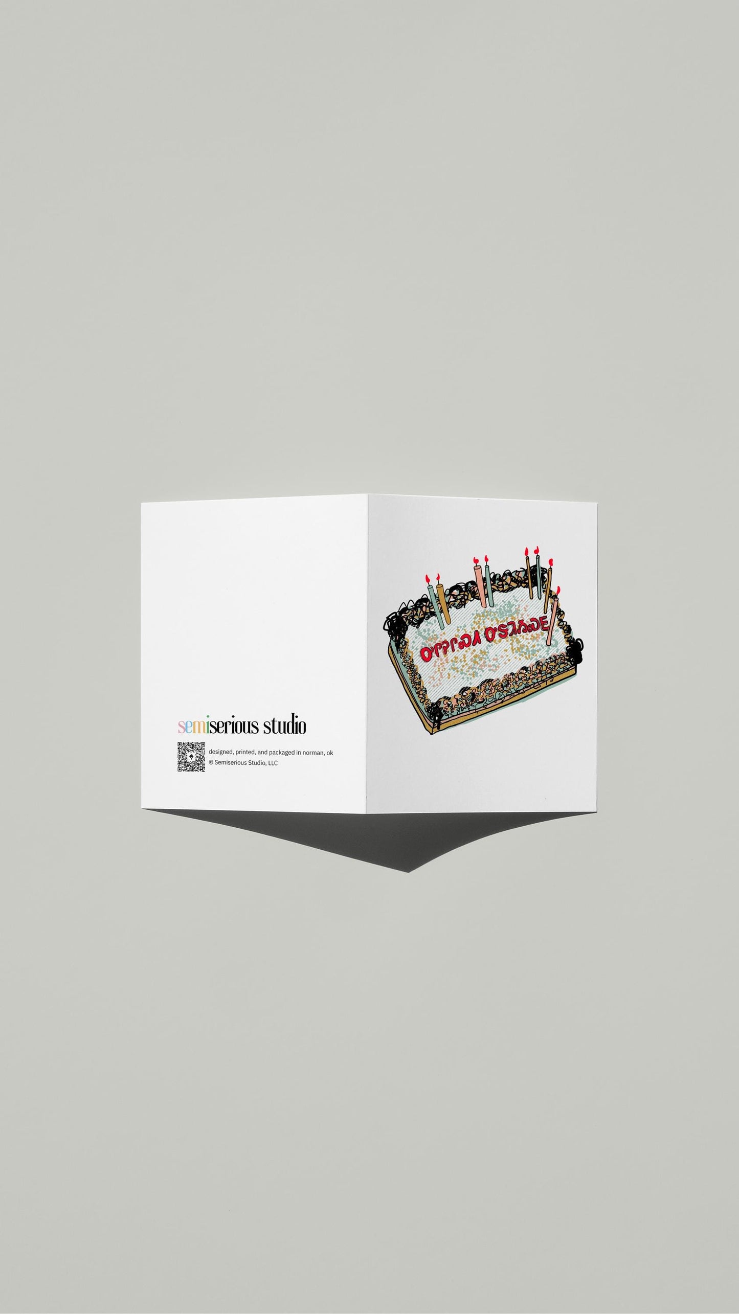 Cherokee Syllabary Birthday card standing open, showing the front artwork and the Semiserious Studio logo on the back