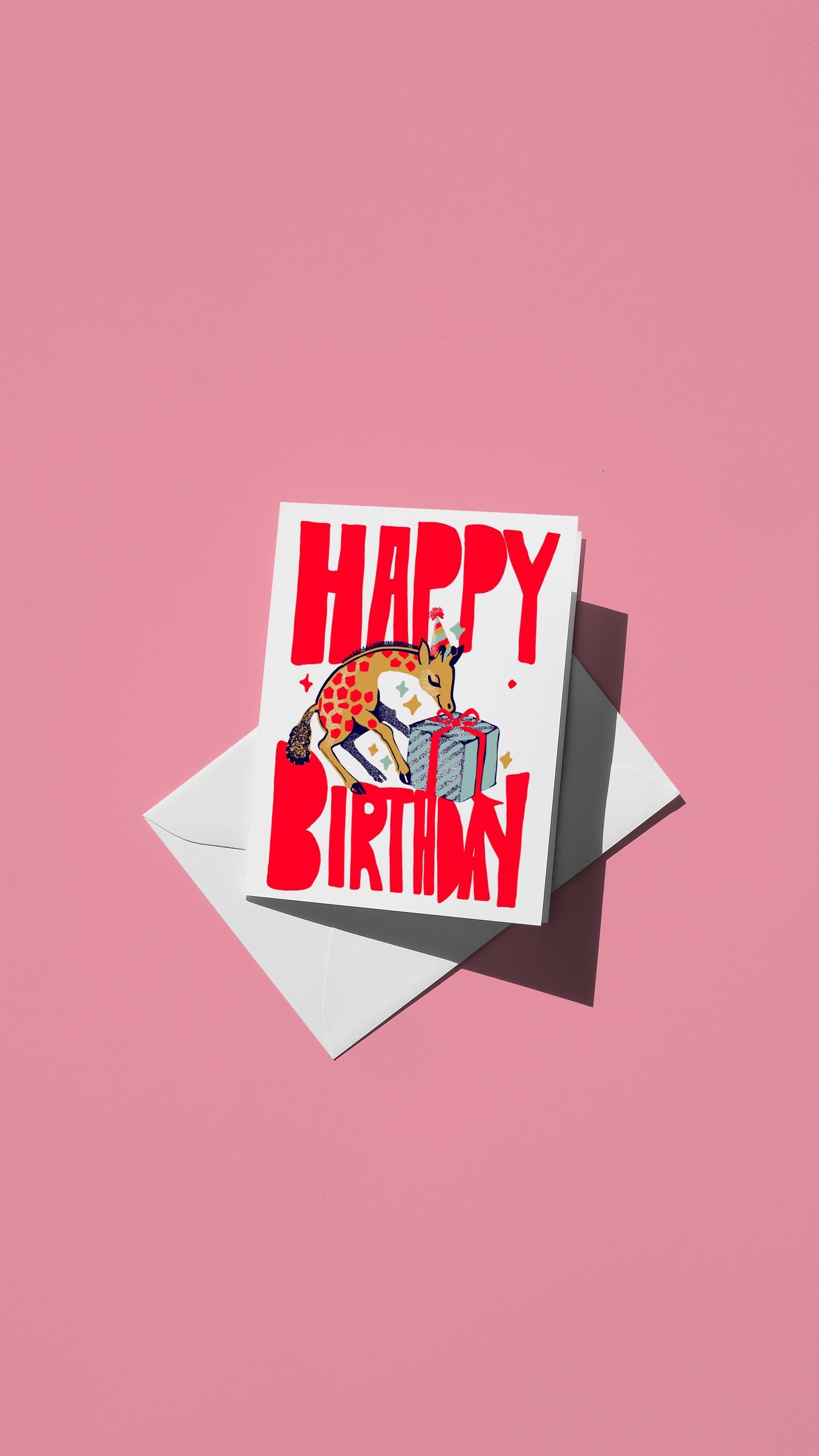 Hand-drawn illustration of a party hat-wearing giraffe unwrapping a birthday present with the message "HAPPY BIRTHDAY" in