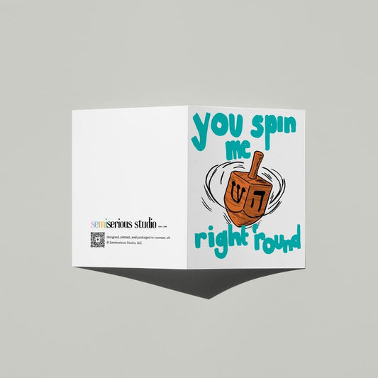Hanukkah Dreidel card standing open, showing the front artwork and the Semiserious Studio logo on the back