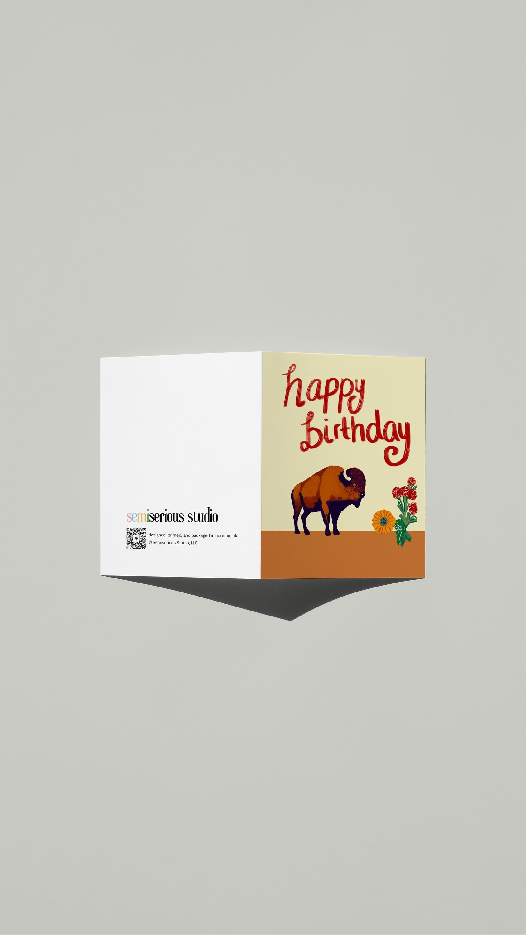 Happy Birthday Bison card standing open, showing the front artwork and the Semiserious Studio logo on the back