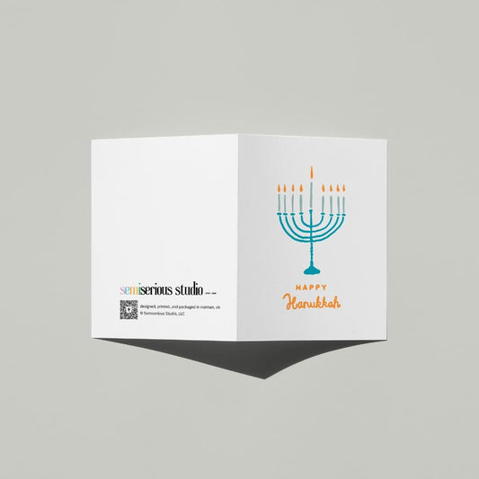 Happy Hanukkah Menorah card standing open, showing the front artwork and the Semiserious Studio logo on the back