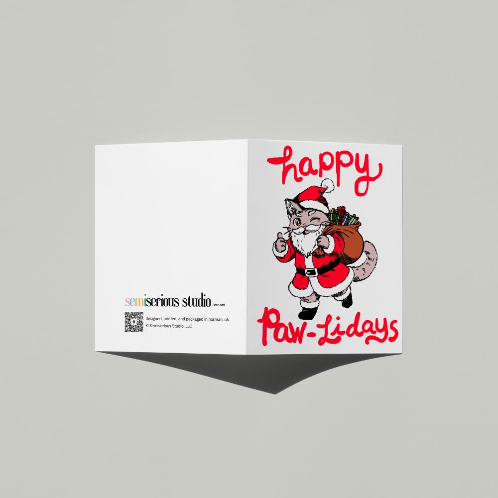 Happy Paw-lidays Cat Santa Christmas card standing open, showing the front artwork and the Semiserious Studio logo on the