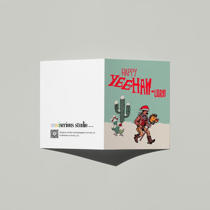 Happy Yeehaw-lidays Cowboy Christmas card standing open, showing the front artwork and the Semiserious Studio logo on the