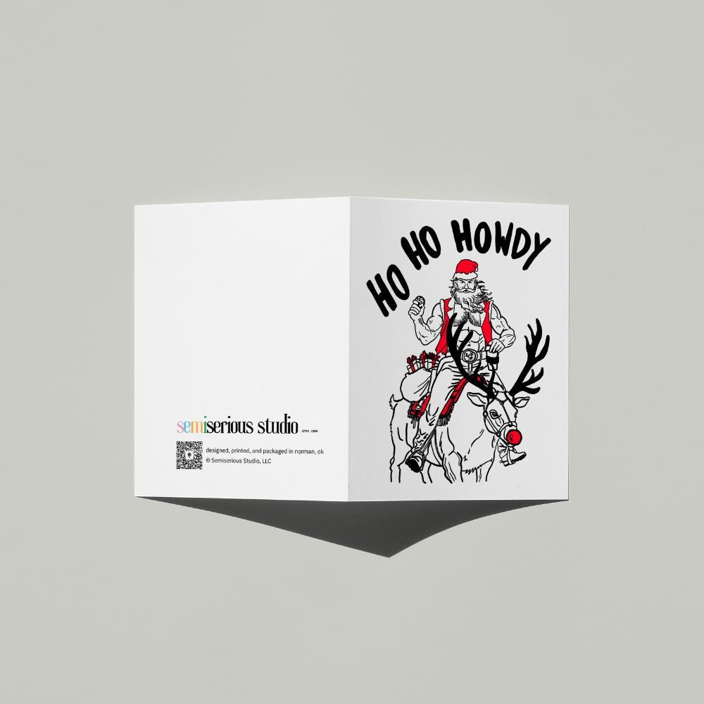 Ho Ho Howdy Cowboy Santa Christmas card standing open, showing the front artwork and the Semiserious Studio logo on the back