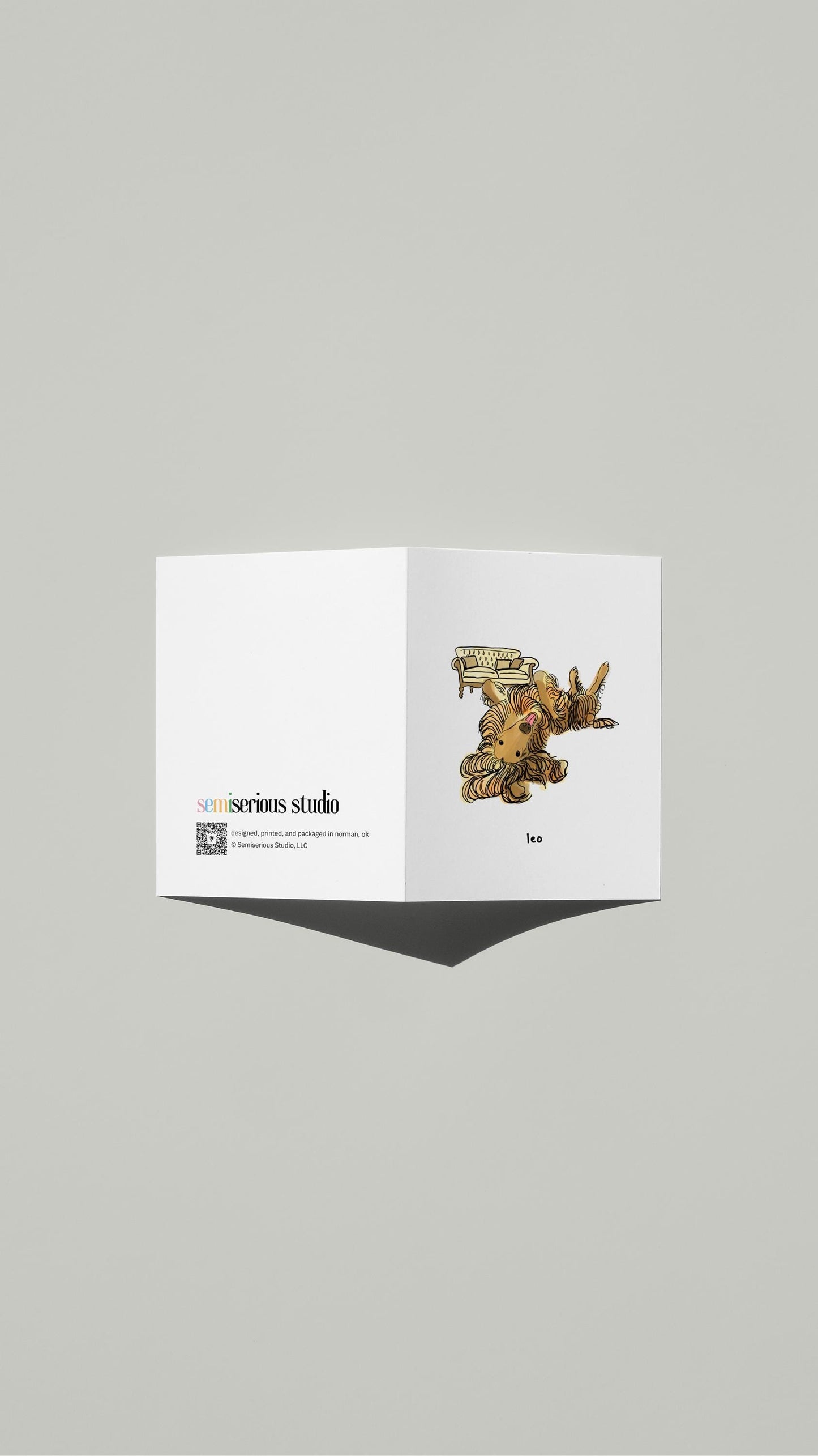 Leo Afghan Hound Birthday card standing open, showing the front artwork and the Semiserious Studio logo on the back