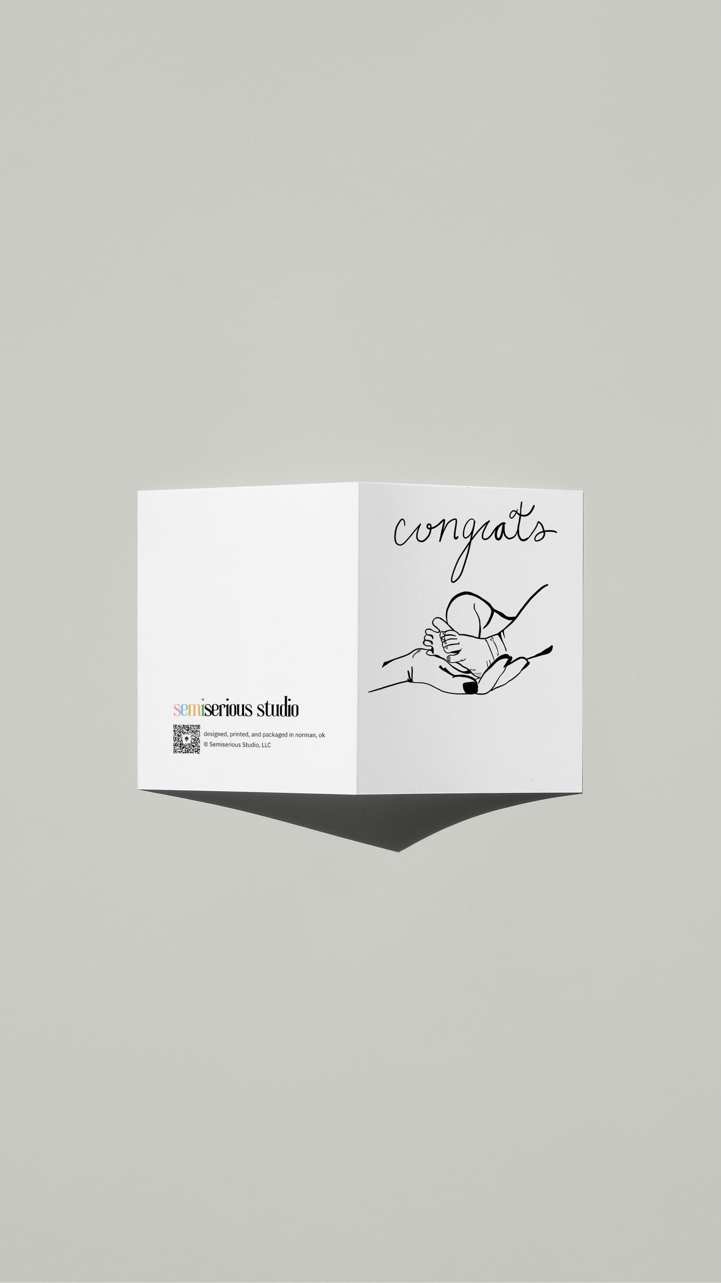 New Baby Congratulations card standing open, showing the front artwork and the Semiserious Studio logo on the back