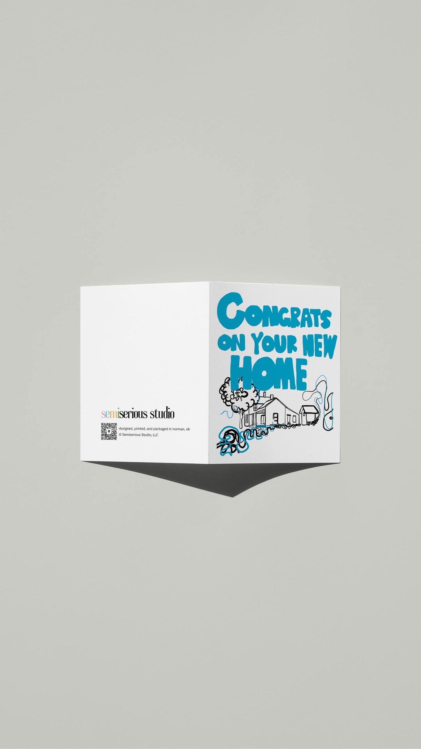 New Home Congratulations card standing open, showing the front artwork and the Semiserious Studio logo on the back