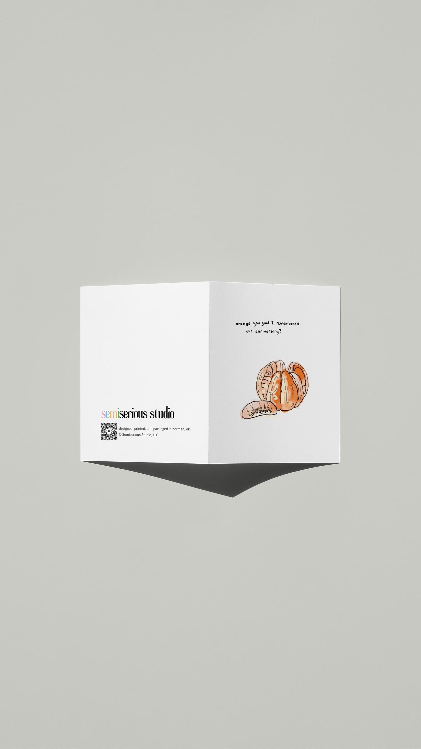 Orange You Glad Anniversary card standing open, showing the front artwork and the Semiserious Studio logo on the back