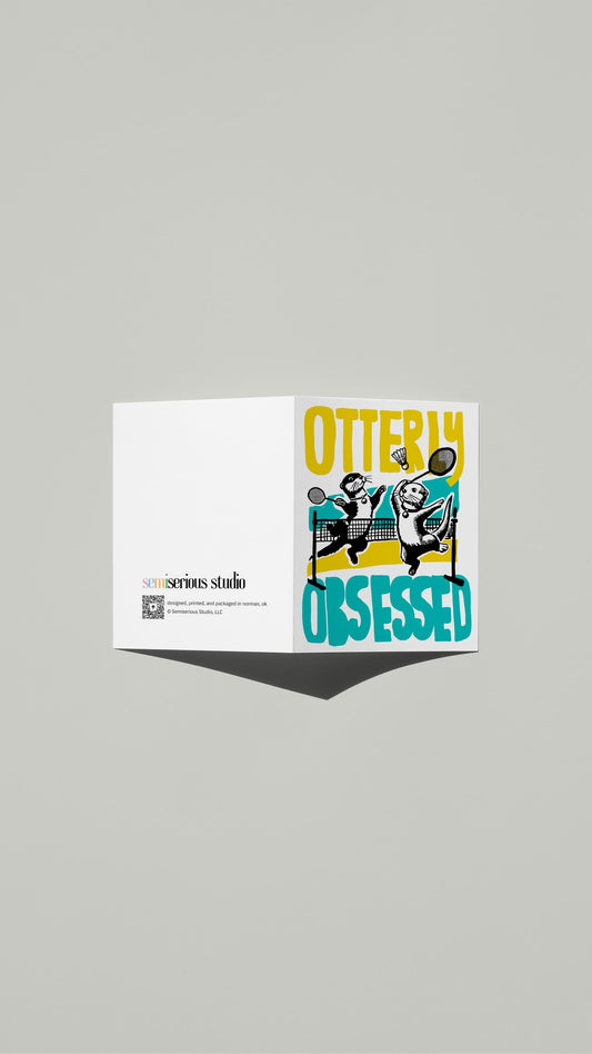 Otterly Obsessed Valentine card standing open, showing the front artwork and the Semiserious Studio logo on the back