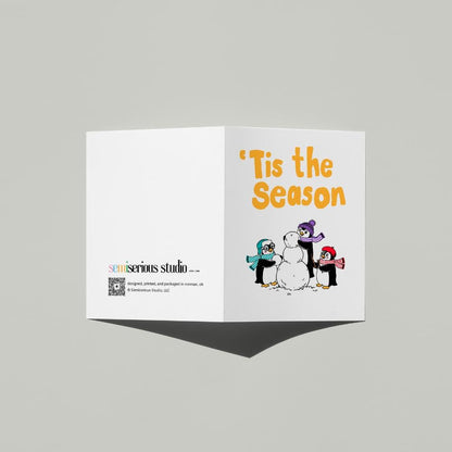 Penguins Building a Snowman Christmas card standing open, showing the front artwork and the Semiserious Studio logo on the