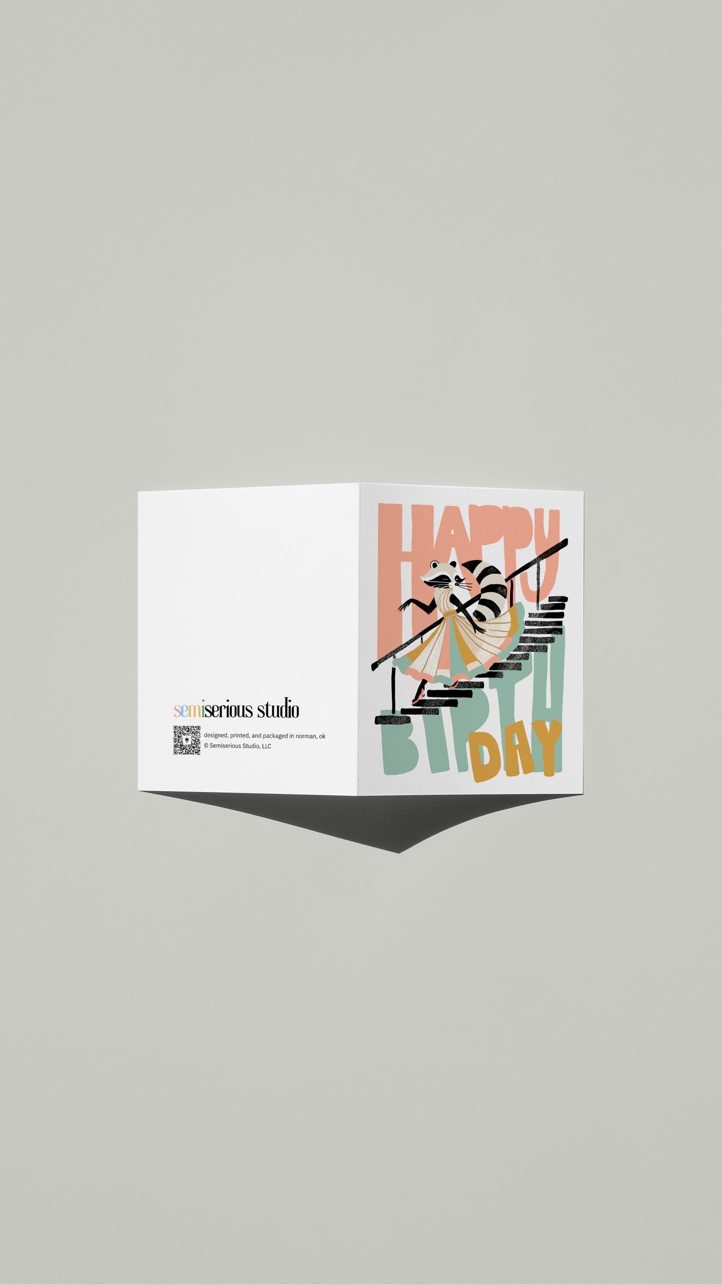 Raccoon Birthday card standing open, showing the front artwork and the Semiserious Studio logo on the back