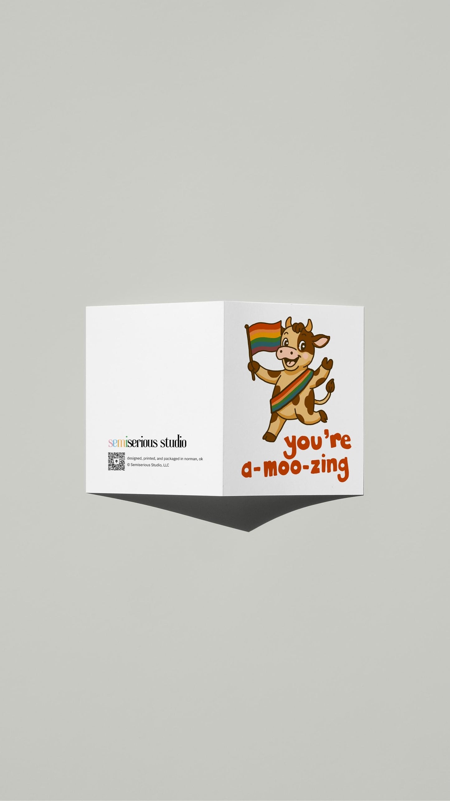 Rainbow Cow Pride card standing open, showing the front artwork and the Semiserious Studio logo on the back