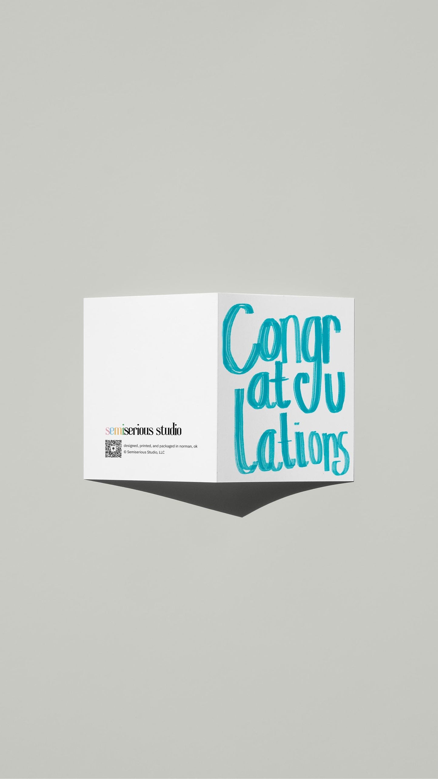Simple Blue Congratulations card standing open, showing the front artwork and the Semiserious Studio logo on the back