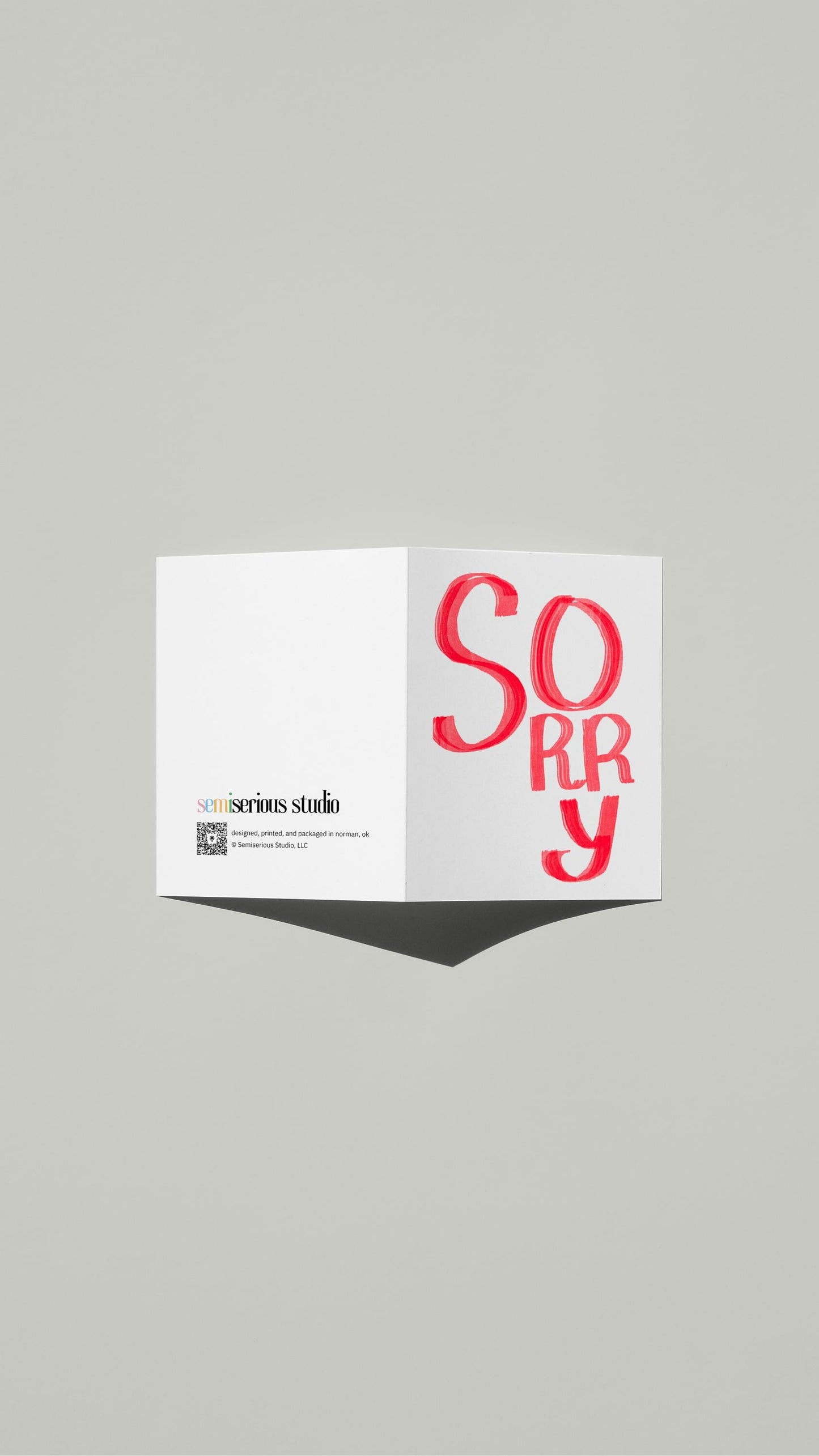 Simple Red Apology card standing open, showing the front artwork and the Semiserious Studio logo on the back