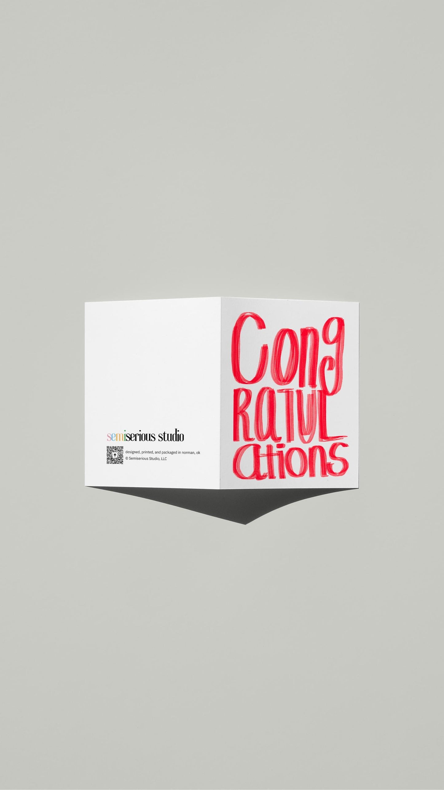 Simple Red Congratulations card standing open, showing the front artwork and the Semiserious Studio logo on the back