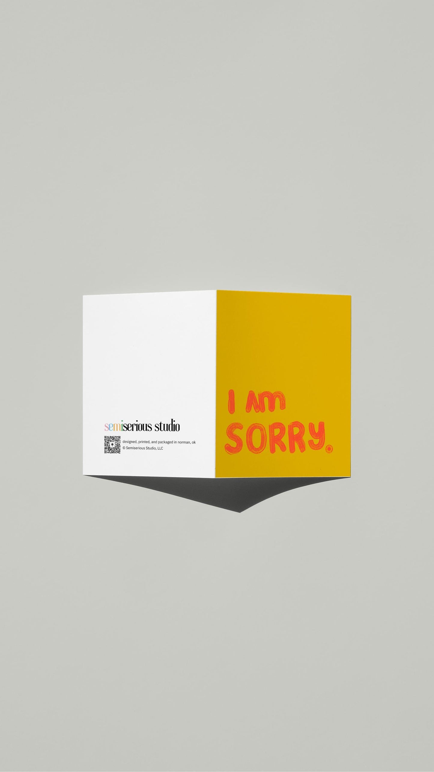 Simple Yellow Apology card standing open, showing the front artwork and the Semiserious Studio logo on the back