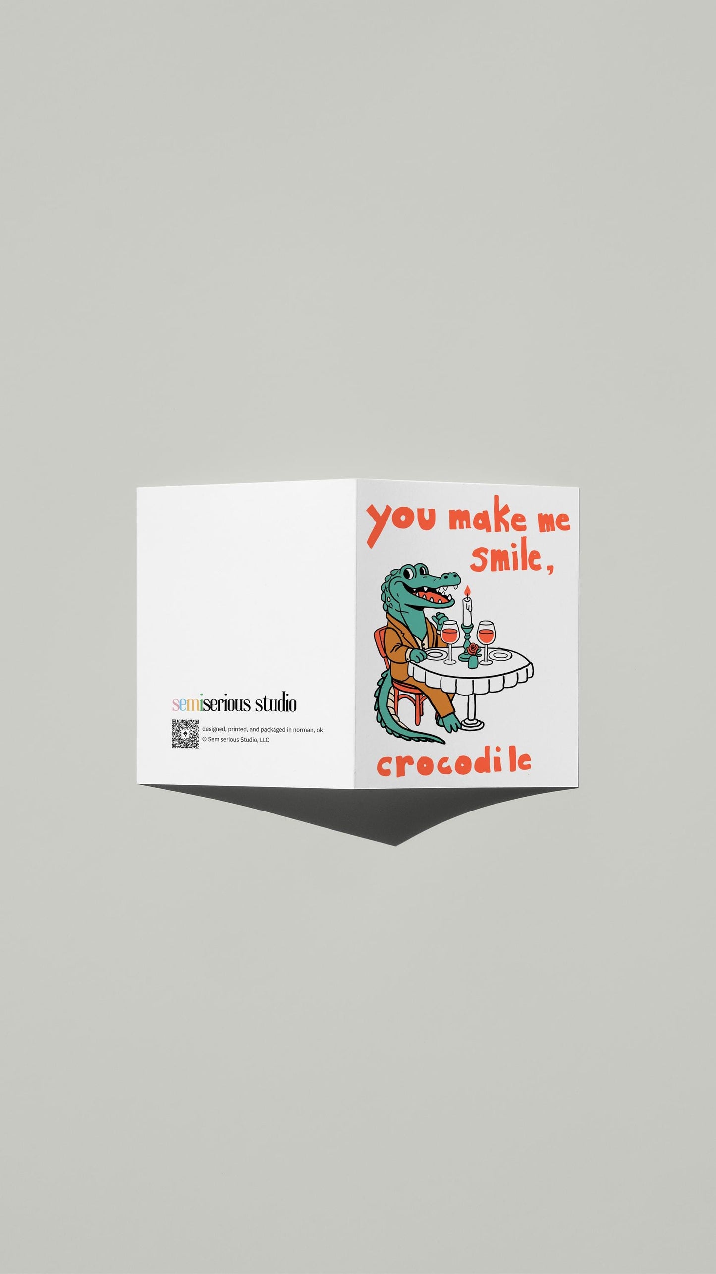 Smile Crocodile Valentine card standing open, showing the front artwork and the Semiserious Studio logo on the back