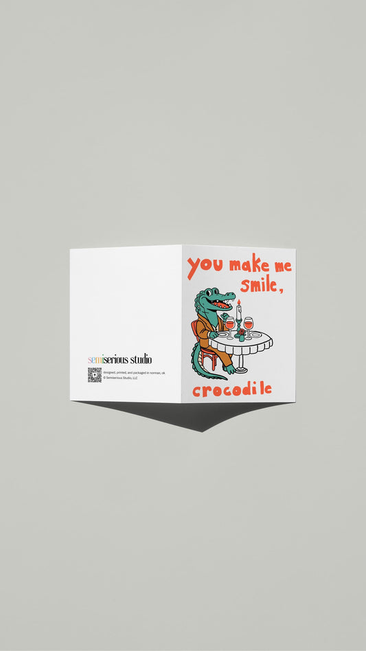 Smile Crocodile Valentine card standing open, showing the front artwork and the Semiserious Studio logo on the back