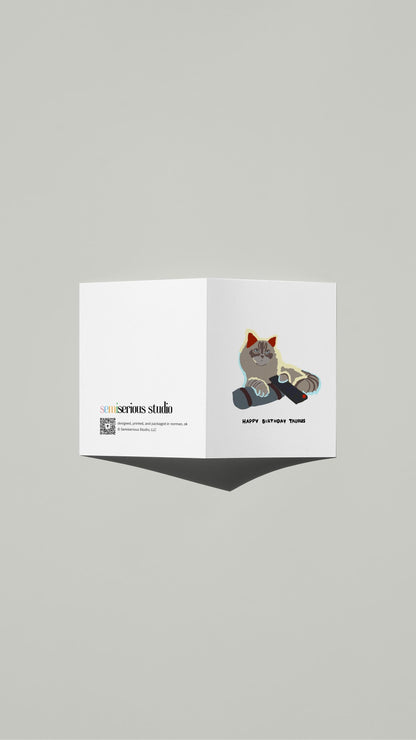 Taurus Cat Watching TV Birthday card standing open, showing the front artwork and the Semiserious Studio logo on the back