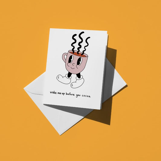 Steaming mug of cocoa with a face, reading "wake me up before you cocoa"