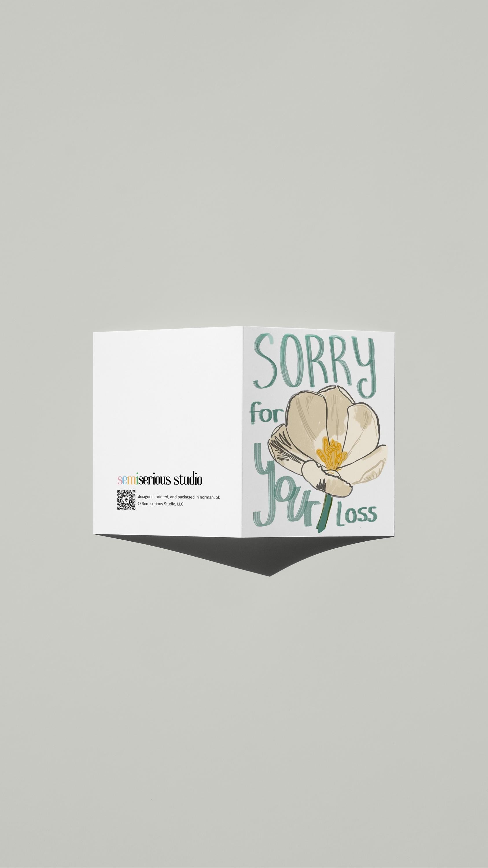 White Flower Sympathy card standing open, showing the front artwork and the Semiserious Studio logo on the back